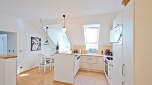 Cozinha moderna com ilha central, piso de madeira e armários brancos.