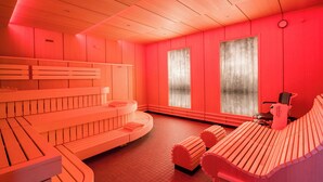 Sala de sauna com bancos de madeira e uma cadeira de massagem.