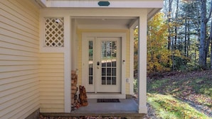 A house with a front porch, a white door, and a small stone statue.