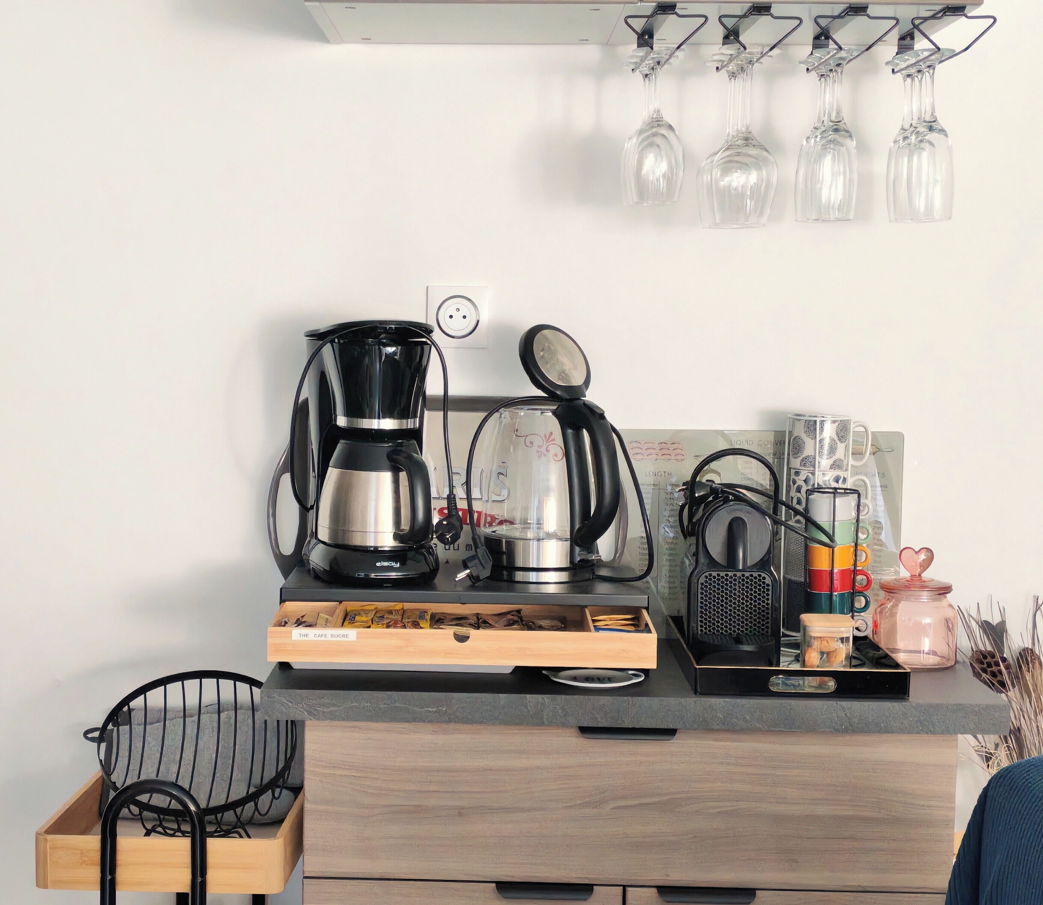 Eine Küchenarbeitsplatte mit Kaffeemaschine, Wasserkocher, Tassenhalterung und einer Schublade mit Etikett.