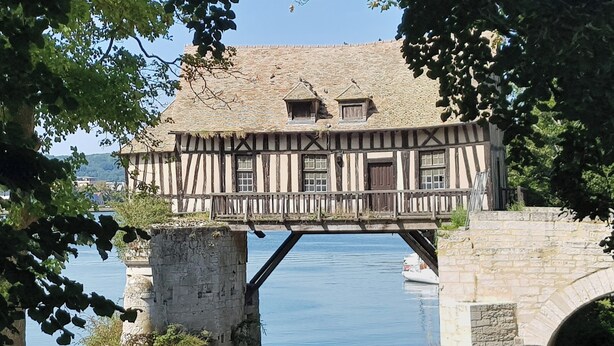 Una casa tradizionale a graticcio con un ponte di pietra su un fiume.