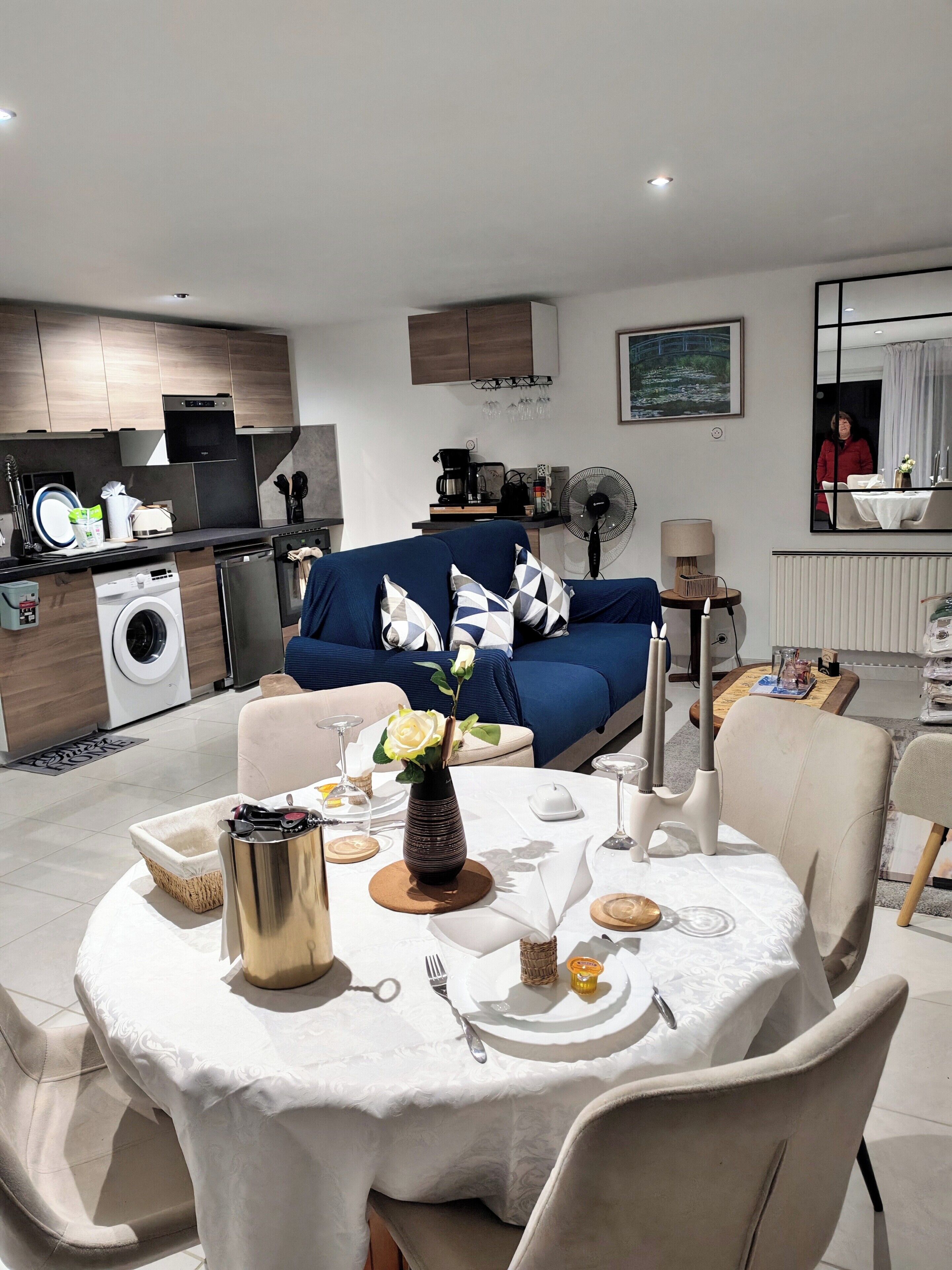 A modern living space with a dining area, kitchen, and a sofa with a decorative pillow.