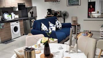 A modern living space with a dining area, kitchen, and a sofa with a decorative pillow.