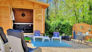 Una baita in legno con camino, mobili in vimini e un patio con tavolo e sedie.