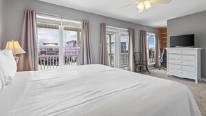 A hotel room with a large bed, a ceiling fan, a TV, and a balcony with curtains. - Gulf view retreat w/ Private pool at Summer Salt! (Gulf Shores)