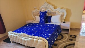 Une chambre à coucher avec un grand lit, une table de chevet, une commode blanche et un tapis à motifs.