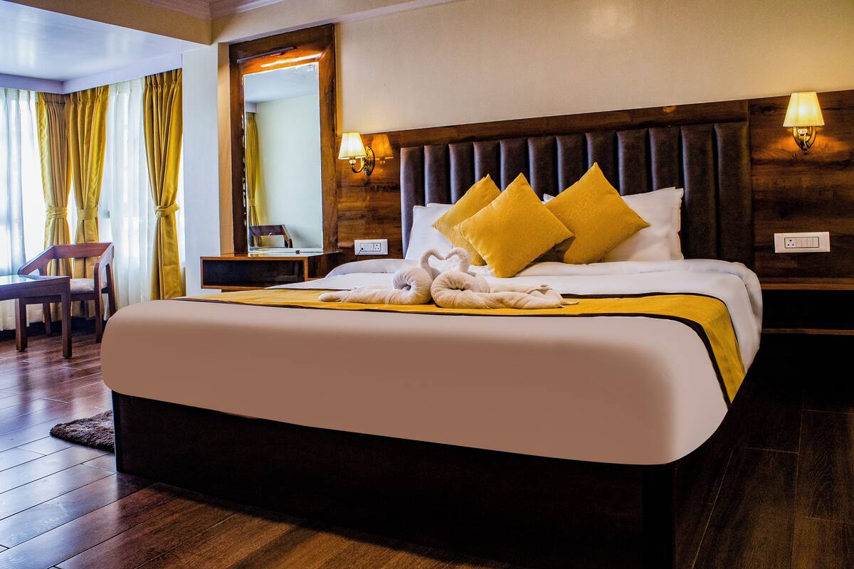 A hotel room with a large bed, wooden headboard, and two bedside lamps.