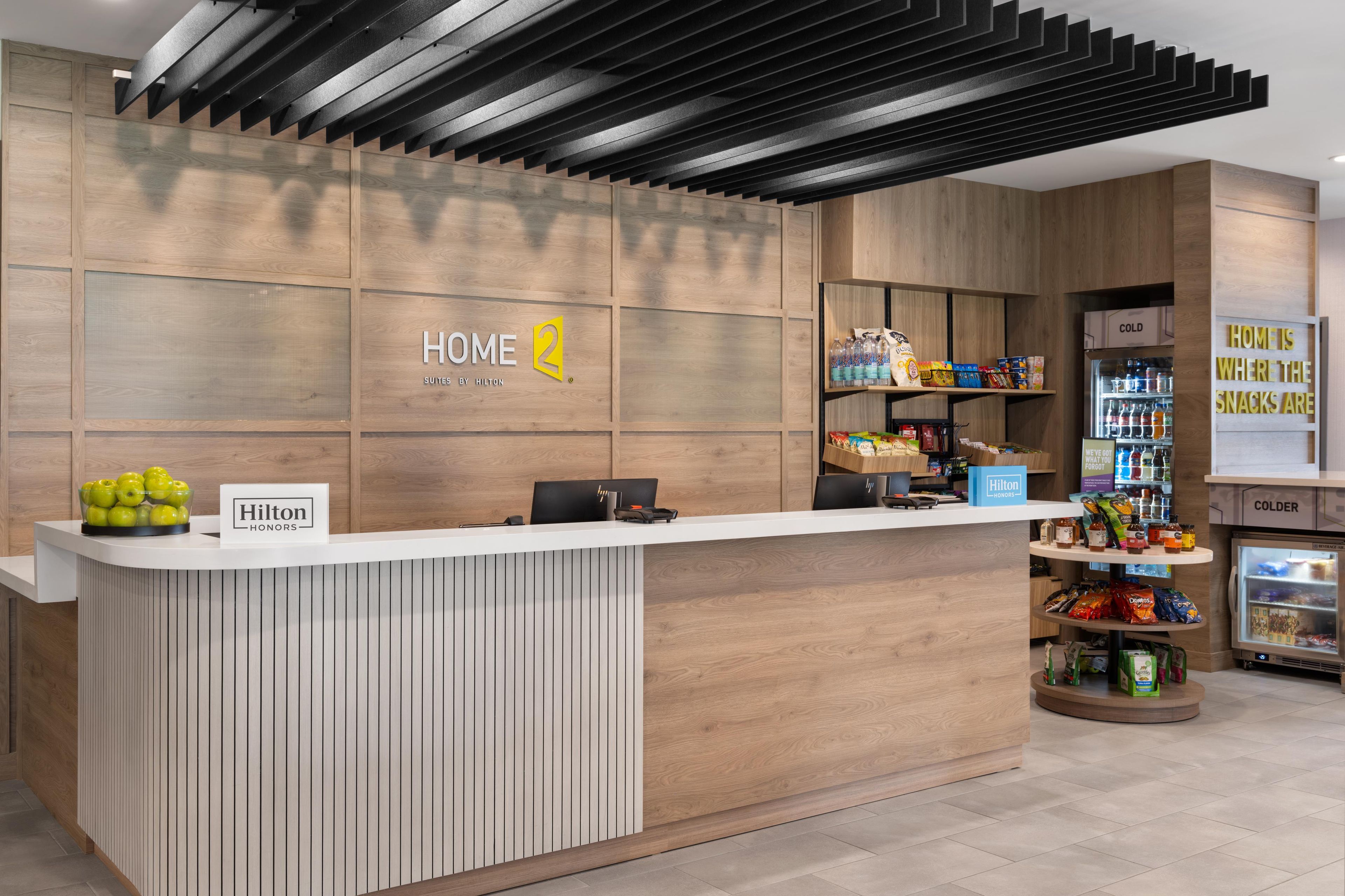 En moderne hotelreception med en væg af træpaneler, et digitalt display og en skranke med et skilt, der siger 'Hilton Honors'.