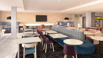 A modern hotel lobby with a mix of seating options including tables, chairs, and a sofa area.