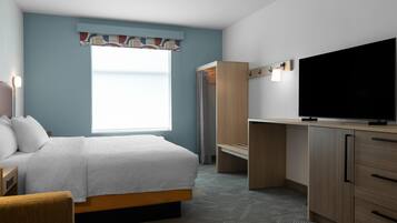 A hotel room with a bed, a desk, a television, and a wardrobe.