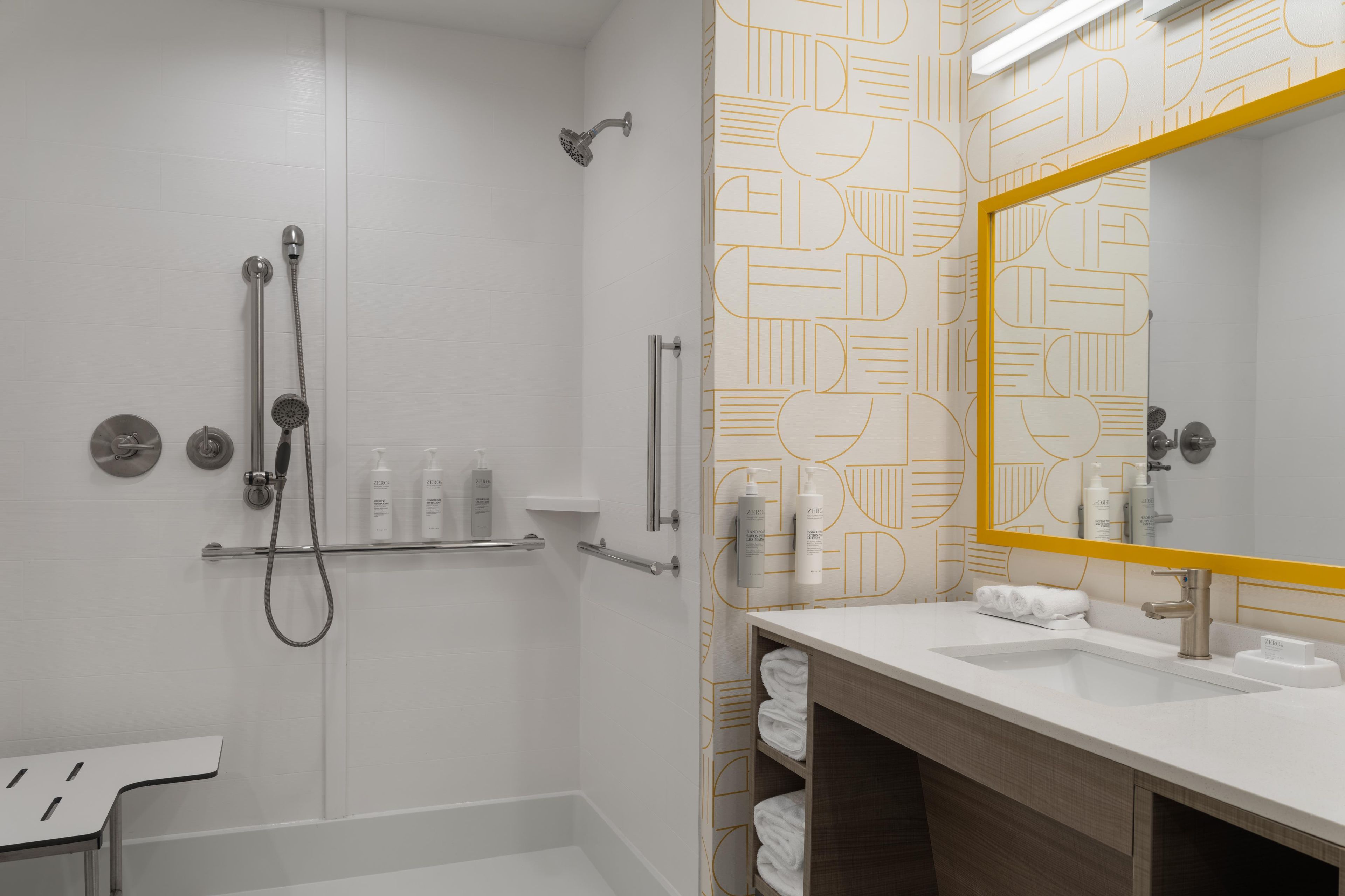 A modern bathroom with a walk-in shower, a vanity with a mirror, and a towel rack.