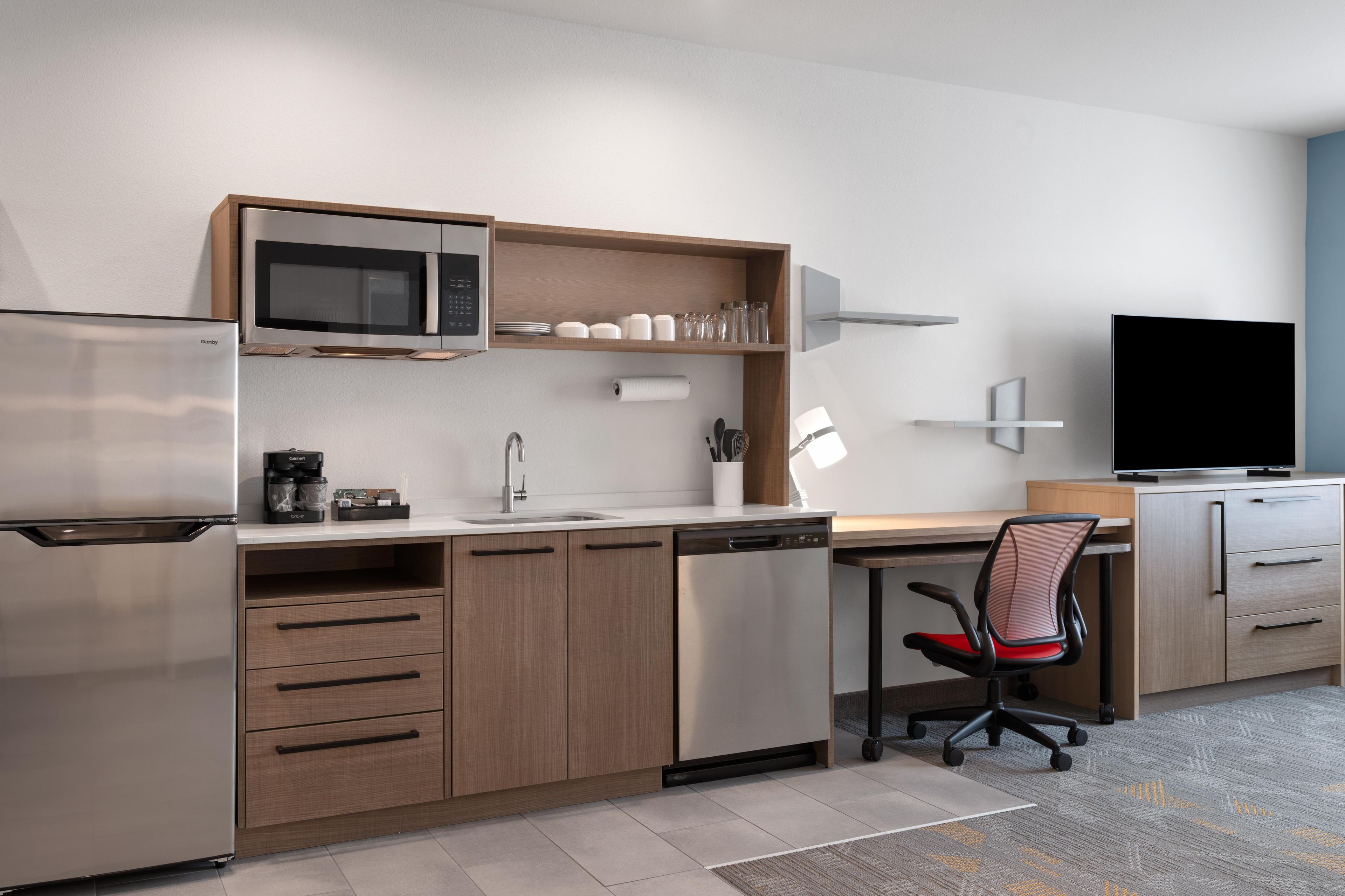 Una kitchenette moderna equipada con microondas, cafetera y lavavajillas.