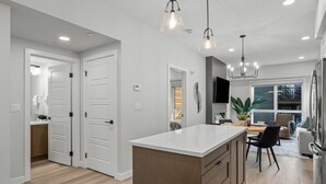 Une cuisine moderne dotée d’un îlot central, de luminaires suspendus et d’un coin repas offrant une vue agréable.