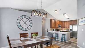 Une cuisine moderne avec des meubles en bois, un réfrigérateur en acier inoxydable et un coin bar équipé de tabourets.