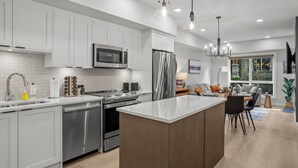 Una cocina moderna con armarios blancos, electrodomésticos de acero inoxidable y una isla central.