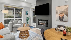 Una sala de estar moderna con chimenea, asientos cómodos y un comedor.