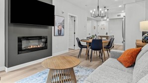 Una sala de estar moderna con chimenea, un comedor y una cocina al fondo.