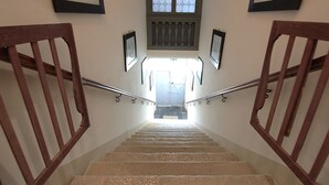 Una escalera con barandillas de madera y vistas del primer piso a través de un ventanal.