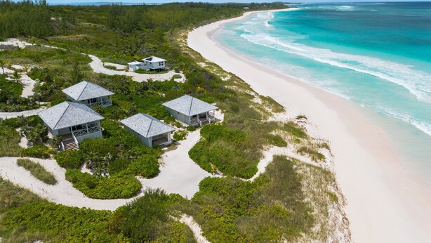 An aerial view of a coastal property with multiple beach houses, a sandy beach, and a clear view of the ocean. - New Luxury Beachfront Bungalows w/Heated Pool, Pink-Sand Beach (Governors Harbour)