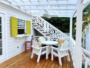 A covered outdoor patio with a wooden deck, white furniture, and a white staircase. - Sea Song on Juicy Hill, Short Walk to Pink Sands Beach (Dunmore Town)