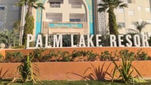 The Palm Lake Resort entrance with a clear sky, palm trees, and a sign above the entrance. - Pool-view apartment in a charming, well-secured residence (Monastir)