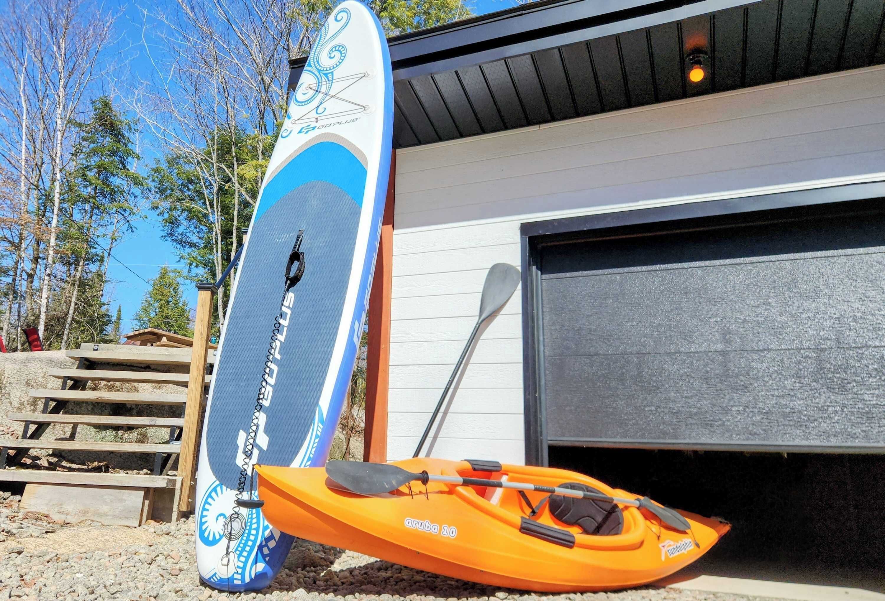 A kayak and paddle leaning against a building.