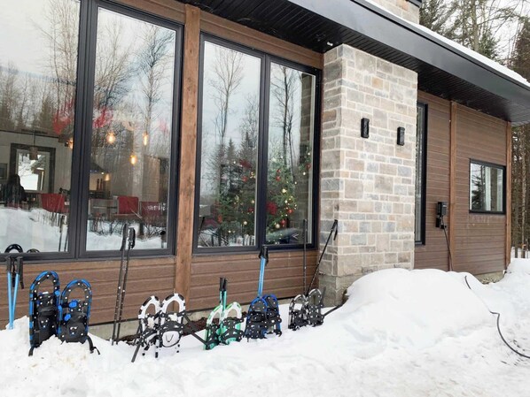 A modern building with large windows, a stone fireplace, and snowshoes outside.