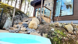 Une maison moderne avec une façade en pierre, une terrasse en bois et une piscine.