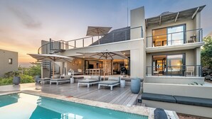 Una moderna casa a più piani con piscina, area salotto esterna e un balcone.