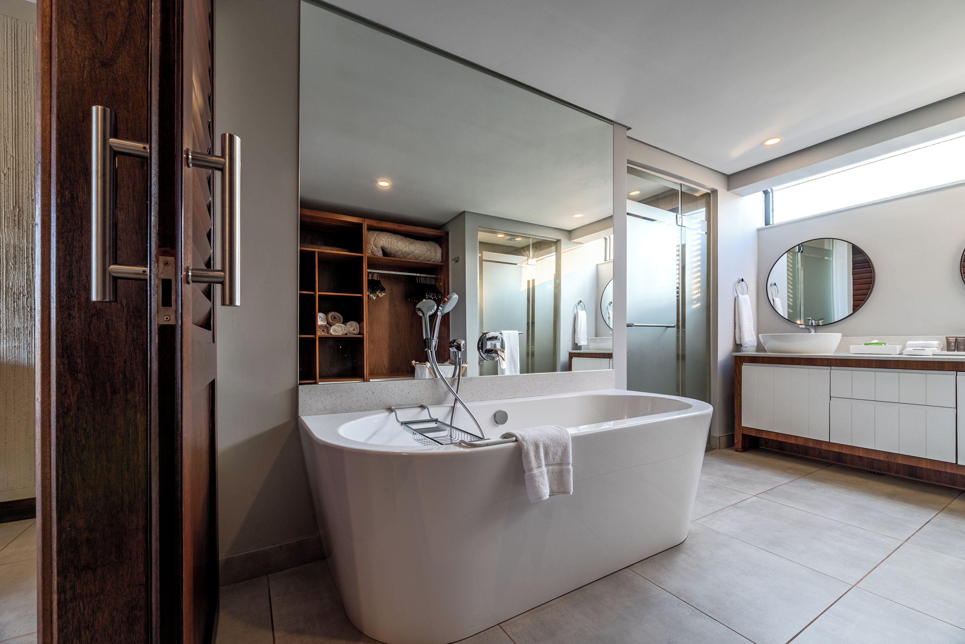 A modern bathroom with a freestanding bathtub, a large mirror, and a walk-in shower.