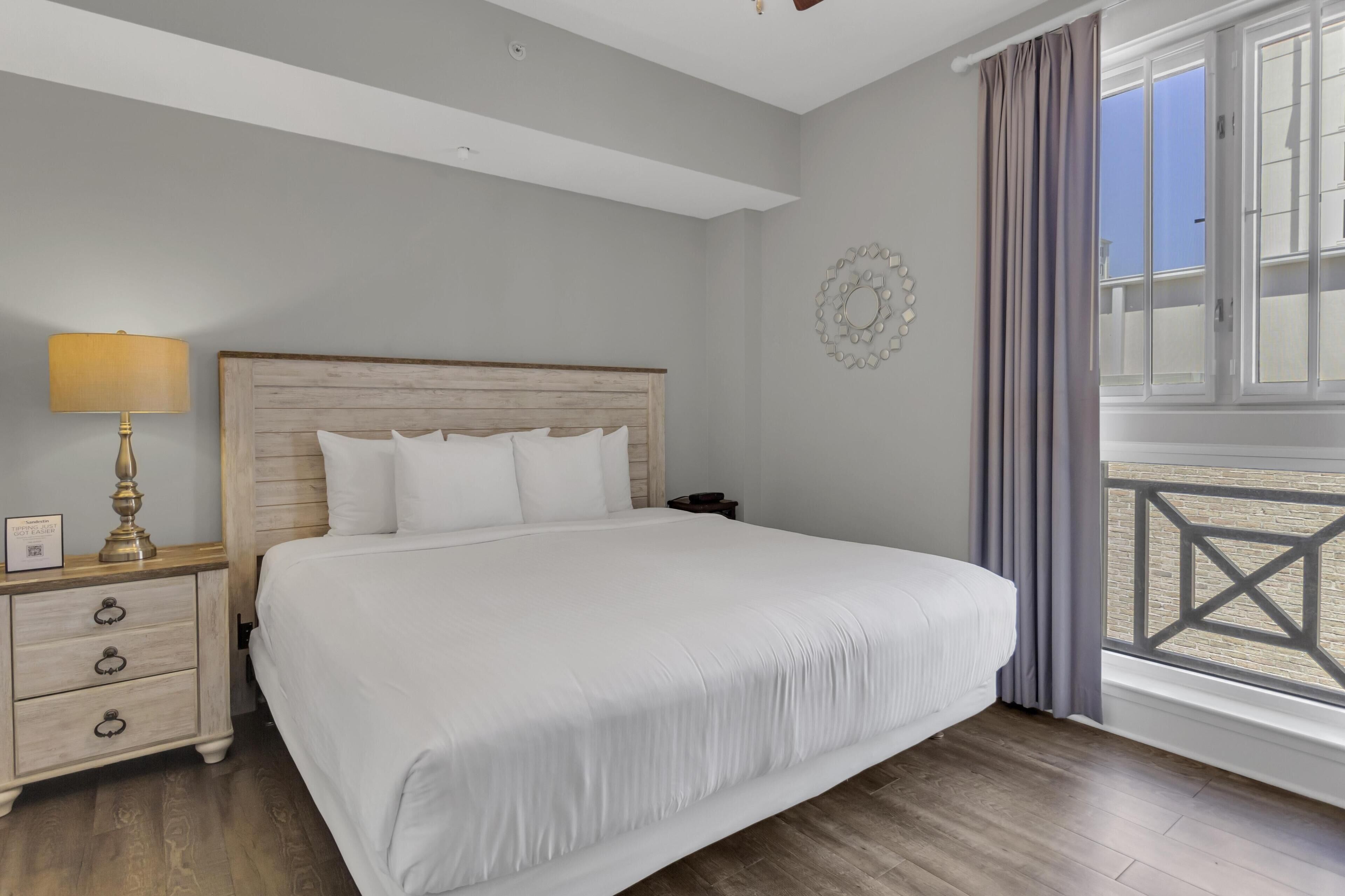 A neatly made bed with a wooden headboard, a bedside lamp, and a nightstand with drawers.