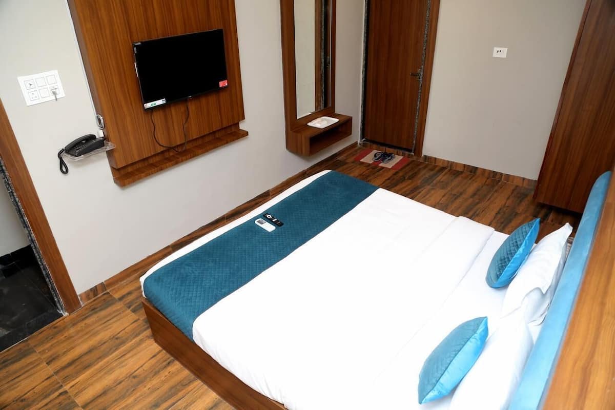 Quarto de hotel com cama, televisão na parede, telefone e espelho.