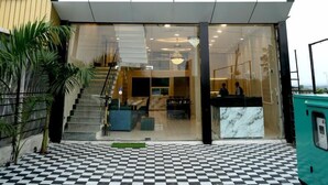 JMC Hotel Safari Inn, med en gulvbelægning i tern og et receptionsskrank, der ses igennem glasdørene.