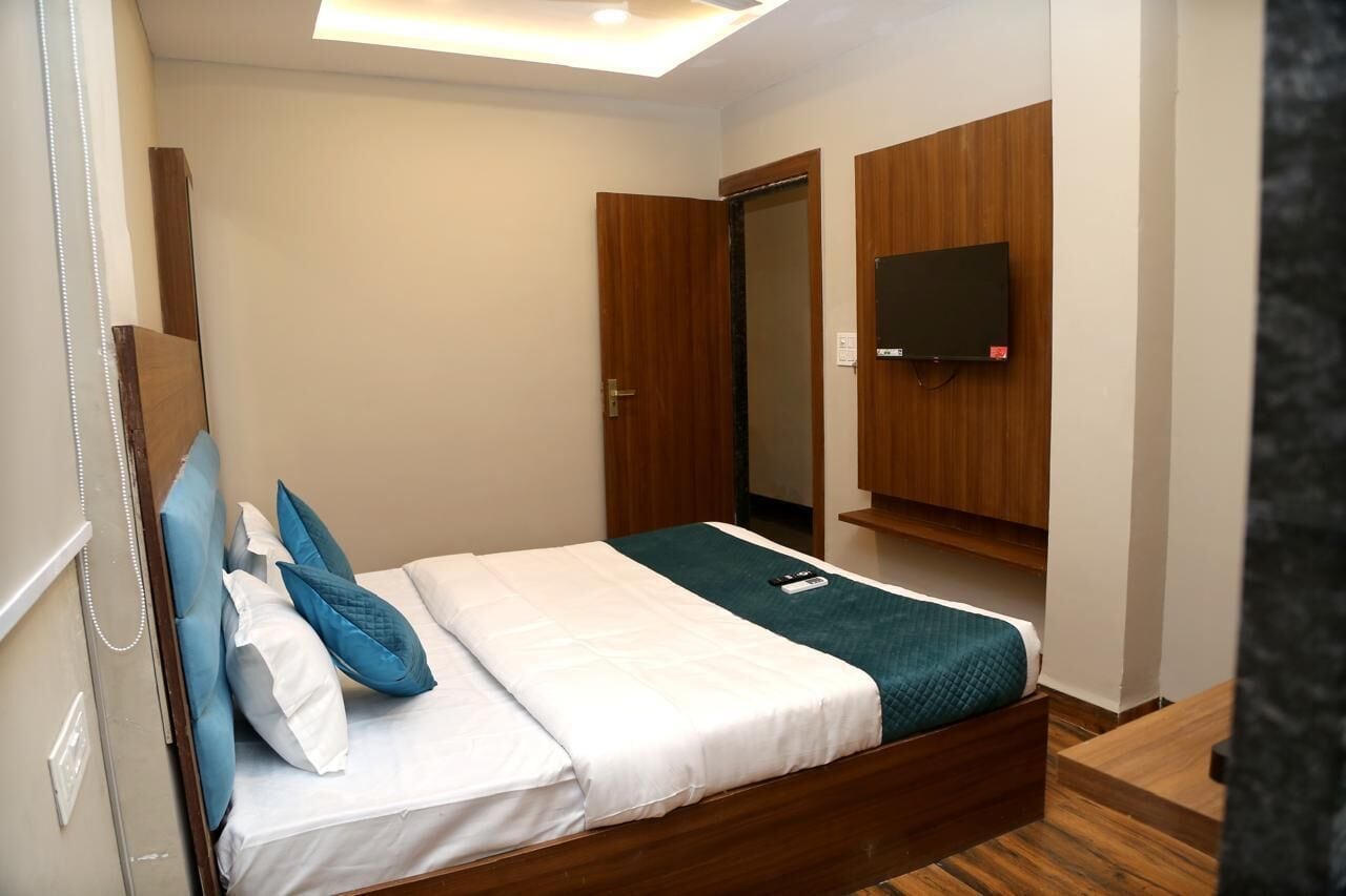A hotel room with a wooden bed, a TV mounted on the wall, and a door leading to another room.