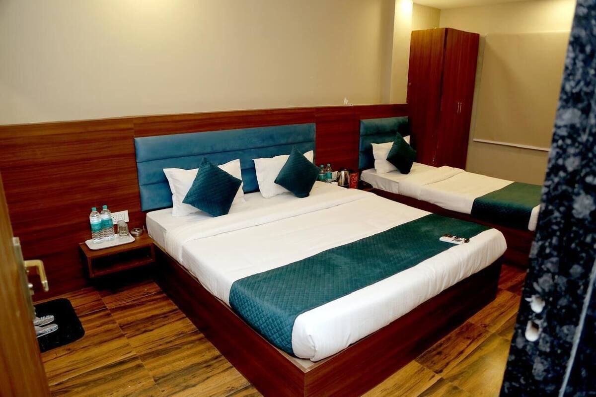 Quarto de hotel com duas camas, cabeceiras de madeira e um guarda-roupa.