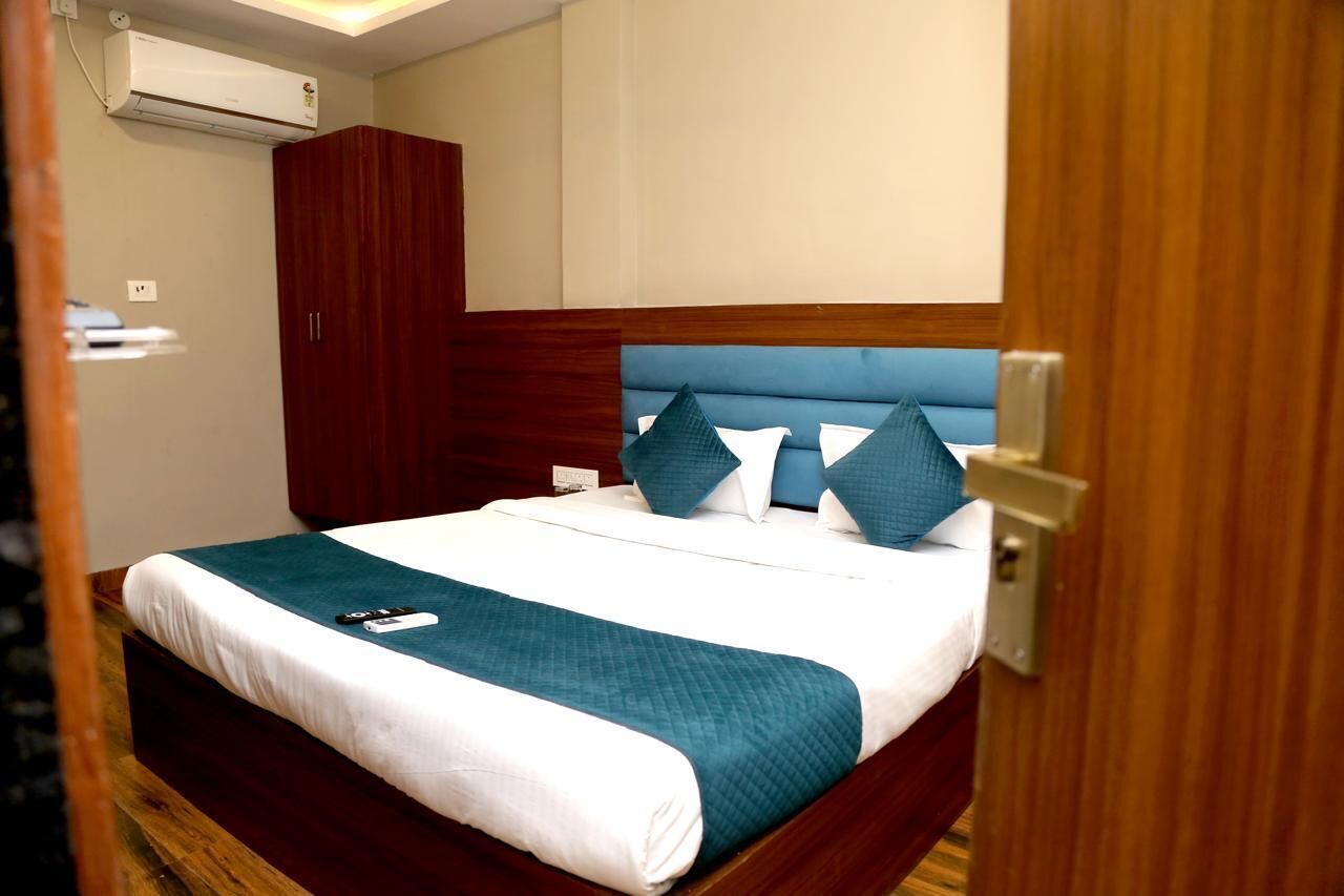 A neatly made bed with a teal and white bedspread, a wooden headboard, and a red wardrobe.