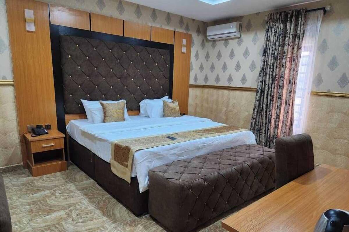 Une chambre d’hôtel avec un grand lit, une table de chevet en bois, un bureau et une chaise.