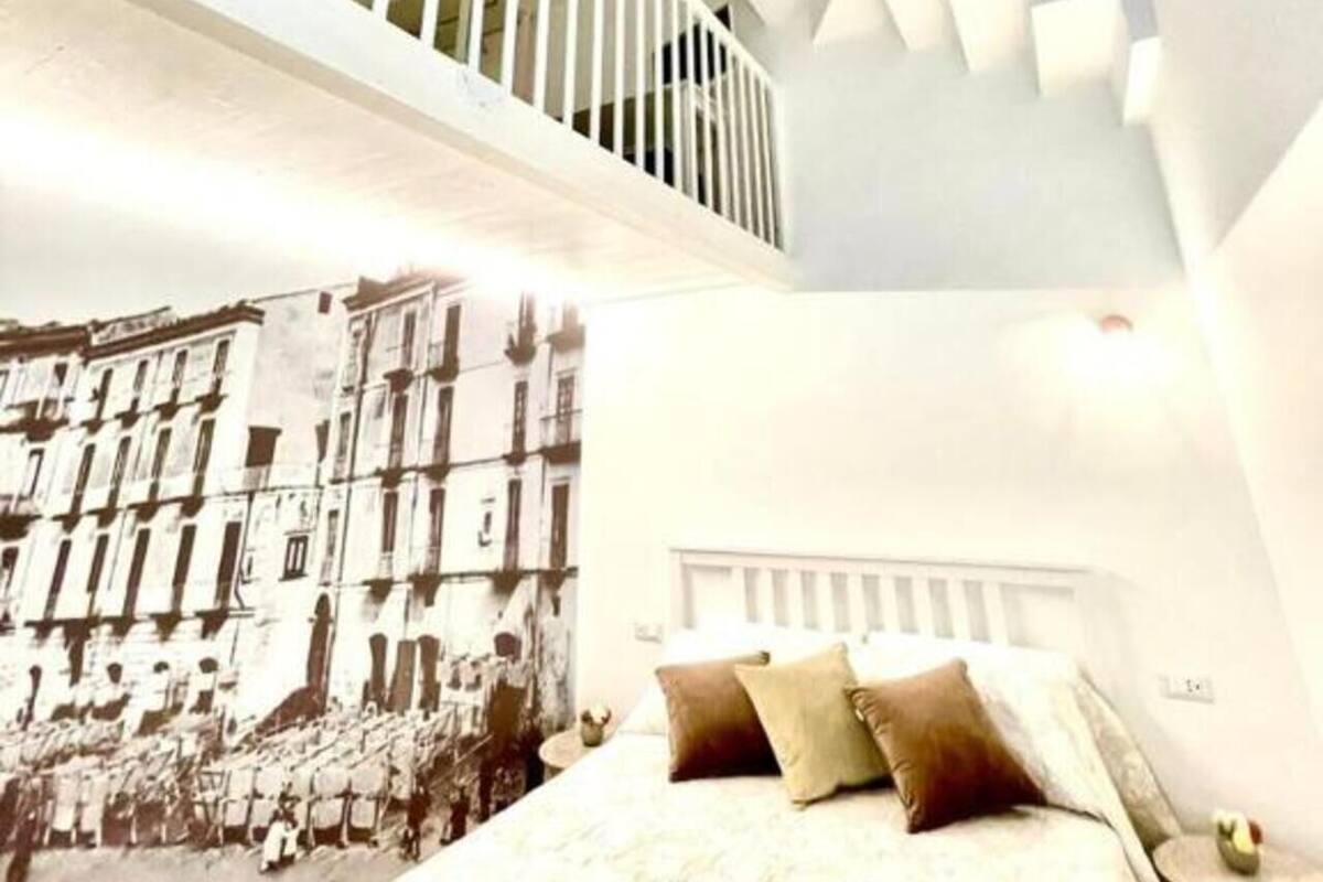A bedroom with a bed, a nightstand, and a wall-mounted shelf.