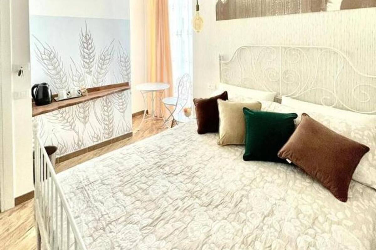 A bedroom with a large bed, a headboard, a hanging light fixture, and a wall with a textured pattern.