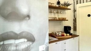 A hallway with a large wall mural, a kitchen area with white cabinets and a wooden countertop, and a patterned wall. - GRANORO B&B (Gragnano)