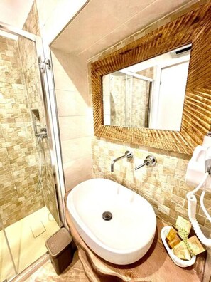 A bathroom with a glass shower enclosure, a white sink, and a mirror with a wooden frame. - GRANORO B&B (Gragnano)