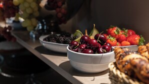 A table with various fruits and pastries, including grapes, cherries, blackberries, strawberries, and bread. - Garibaldi Palace (Milan)