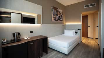 Hotelkamer met een bed, nachtkastje en een bureau met een koffiezetapparaat.