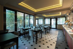 Een moderne eetruimte met grote ramen, betegelde vloer en modern verlichting.