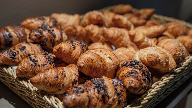 A basket filled with assorted pastries, including croissants and chocolate-covered items. - Garibaldi Palace (Milan)