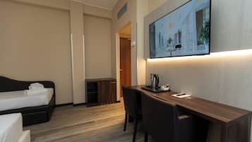 Een hotelkamer met een bed, een bureau en een stoel. Er hangt een schilderij aan de muur en een raam met uitzicht op gebouwen.