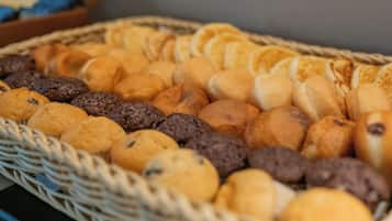 Una cesta repleta de productos horneados, como galletas, magdalenas y panecillos.