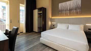Una camera d'albergo con un letto grande, una scrivania e un armadio.