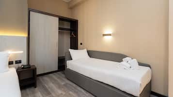 Camera d'albergo moderna con un letto singolo, un comodino con lampada, un armadio e una luce a parete.