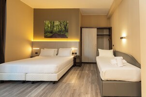 Habitación de hotel con dos camas, un cuadro de un bosque en la pared y un armario.